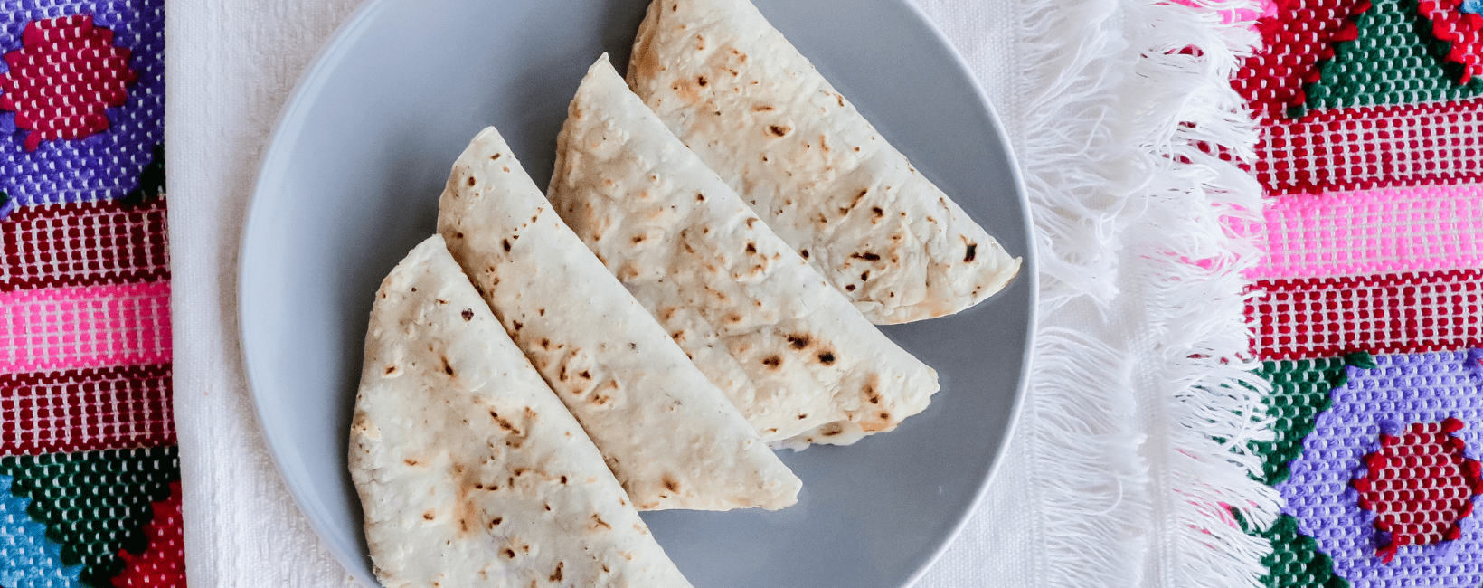 Een courgette en feta quesadilla op een bord, gemaakt van twee tortilla's gevuld met gebakken courgette, ui, knoflook en verkruimelde feta kaas.